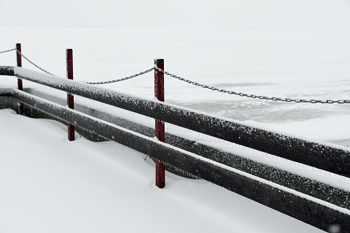Beautiful winter landscape of Wooden fence with chain on the snow-covered ice of the river. Clean winter season concept.