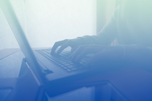 Woman typing on keyboard, blue background