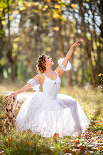 Mature ballet dancer in the forest posing with his old dance shoes in his hands