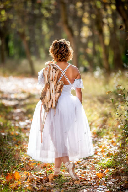 ballet dancer walking in the forest in autumn with all his old dance shoes in his back