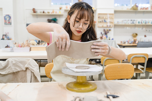 A girl who is making clay pots in the pottery studio