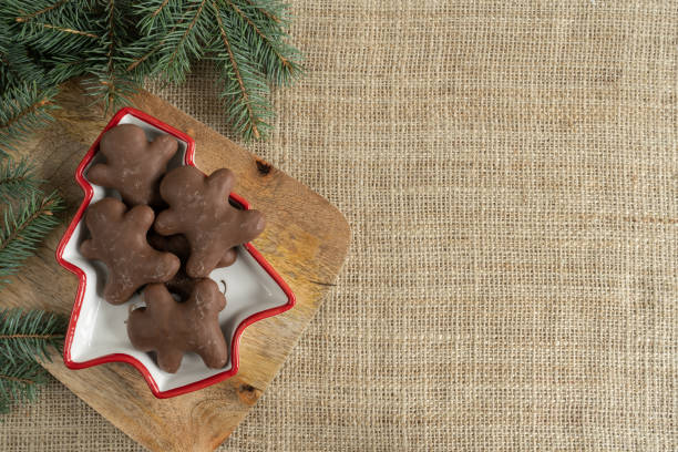 istock Chocolate gingerbread man Christmas cookies, tree branches and copy space on jute. 1446681074