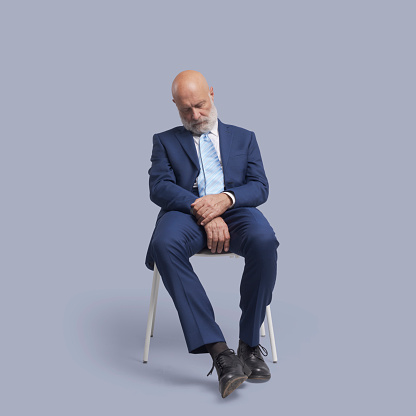 Senior corporate businessman sitting on a chair and sleeping
