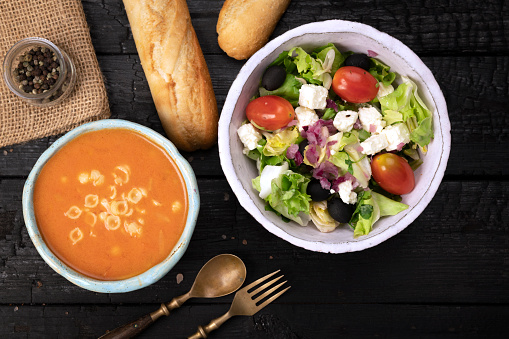 Tomato soup and greek salad on table.