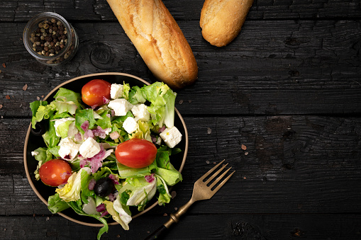 Greek salad on Black wooden table. Space