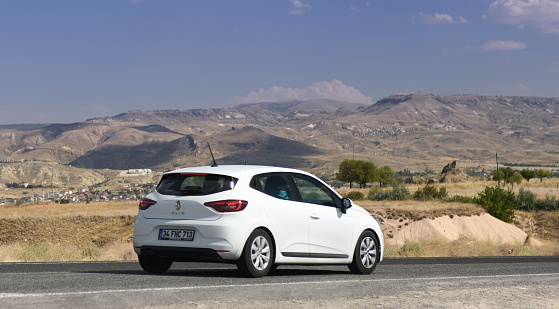 Cappadocia, Turkey 07.12.2022: White Renault Clio is moving in the mountains of Cappadocia. Renault Clio is a supermini car (B-segment) produced by the French automaker Renault.