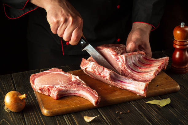 istock Cutting raw ribs with butcher hands on kitchen cutting board. Barbecue grill idea 1446690166
