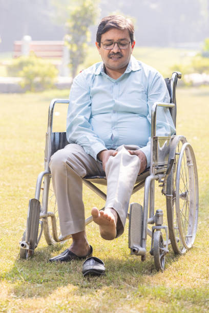 Happy senior man in wheelchair smiling enjoying freedom walking on road in city park outdoor. Old cheerful positive man in chair for people with disability. Disability disease rehabilitation