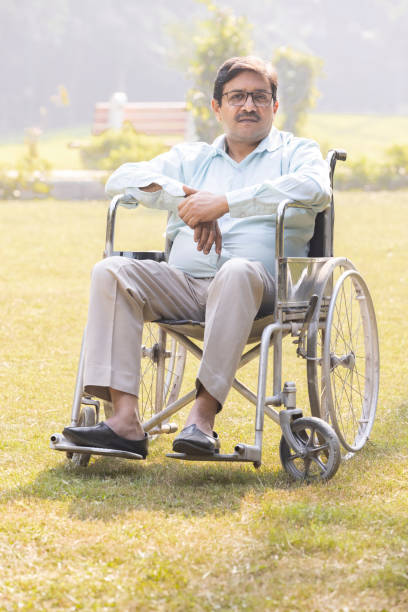 Disable senior man sitting in wheelchair at park and doing leg exercises.