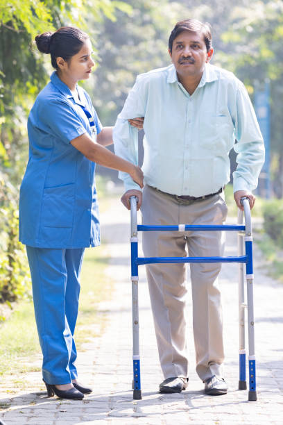 istock A senior man using a zimmer frame alongside his caregiver while out in the garden. 1446690583