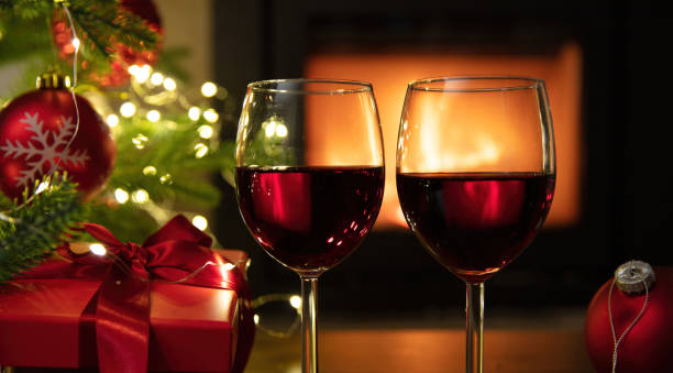 istock Christmas celebration. Red wine glasses, Xmas presents and decoration on table, fireplace background. Xmas celebration 1446691231
