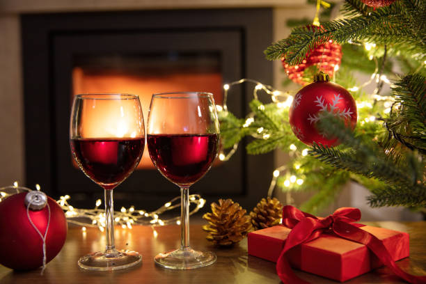 istock Christmas celebration. Red wine glasses, Xmas presents and decoration on table, fireplace background. Xmas celebration 1446691238
