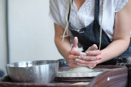 Female Potter creating a earthen jar on a Potter's wheel.