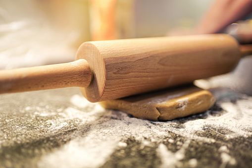 baker pressing bread dough with rolling pin