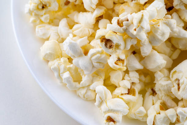 Close-up view of woman picking up popcorn from machine.