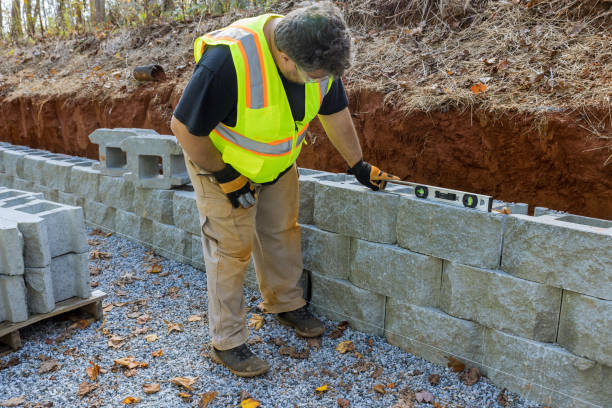 istock Man with leveling tool building retaining block wall with being built on new property 1446699487