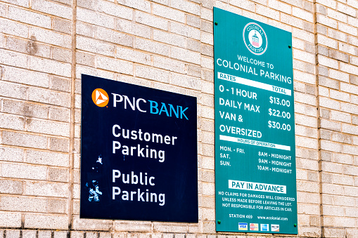 Washington DC, USA - August 18, 2021: Georgetown M street with PNC bank entrance sign on wall closeup for customer public colonial parking with rates price for hours parked