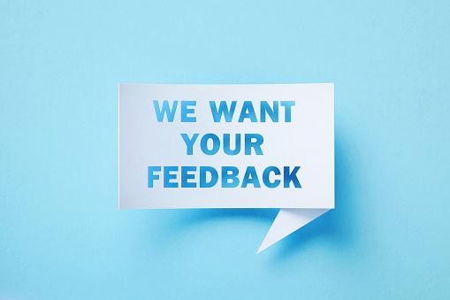 We want your feedback written white chat bubble with cutout e-mail symbol sitting on blue background. Horizontal composition with copy space.