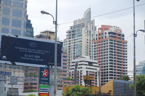 Bangkok Skyline in Silom Sathon area. In bottom area is a gasoline station Caltex. In background are tall condominiums. At left side is a banner for new condominium