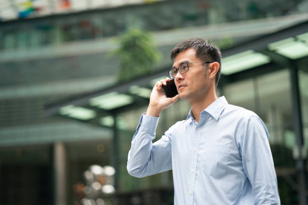 istock Asian male using mobile phone while walking in Singapore's Central Business District 1446711821