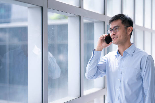 istock Asian Male using mobile phone near window in generic office 1446712249