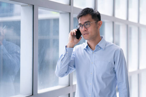 istock Asian Male using mobile phone near window in generic office 1446712252