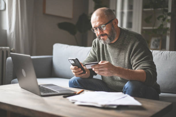 istock mature adult man working at home ( laptop, financial bill, credit card, smart phone) 1446713528