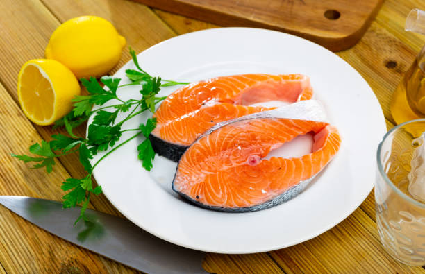 istock Raw salmon steaks on plate with greens, lemon and garlic 1446716323