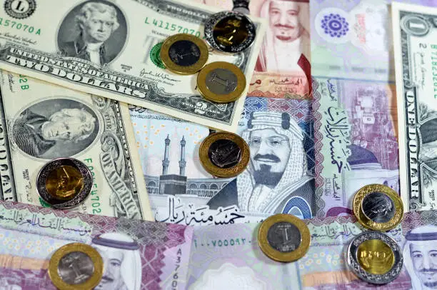 Background of American dollars cash money banknotes and coins with Saudi Arabia kingdom money bills and coins, Saudi and American currency exchange rates, oil and financial concept of middle east, selective focus