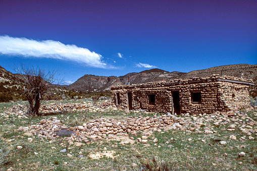 Under the bright blue sky in a remote location sits an abandoned hand built stone home in New Mexico.