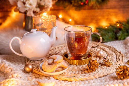 Christmas winter cup of black tea in rustic home with tea pot and Christmas lights