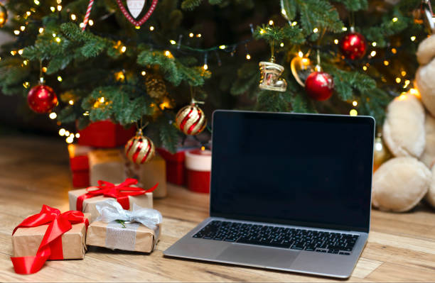 istock A laptop with space for a copy on a wooden background under a Christmas tree. 1446720546