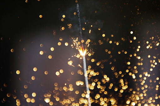 Eine Wunderkerze von einer Silvester Party mit Glitter Effekt als Hintergrund.