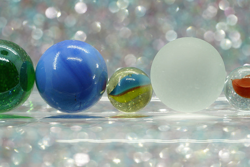 Glass balls and colorful marbles against a light blurred background