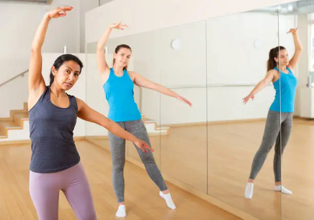 Photo of Hispanic woman practicing classic dance moves during group class