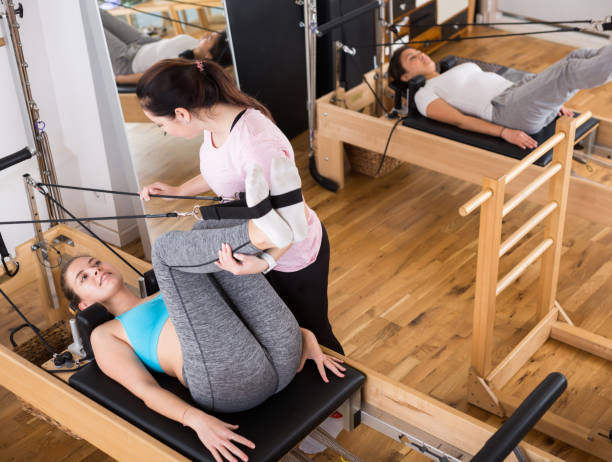istock Female pilates trainer helping pilates woman during training 1446728207