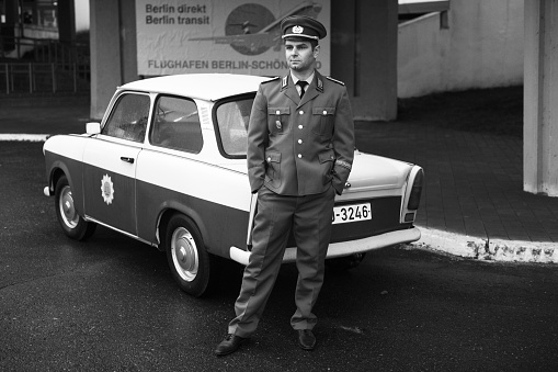 Belarus, Minsk - 30.11.2022:A border guard from East Berlin near a retro police car Trabant. Interflug is the state-owned airline of the German Democratic Republic.Police car Trabant (Trabi) 601a.