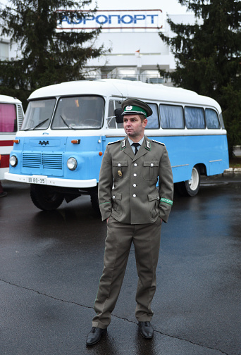 Belarus, Minsk - 30.11.2022: Border guard from East Berlin near Retro bus Robur parked at the airport. Bus Robur from the GDR.