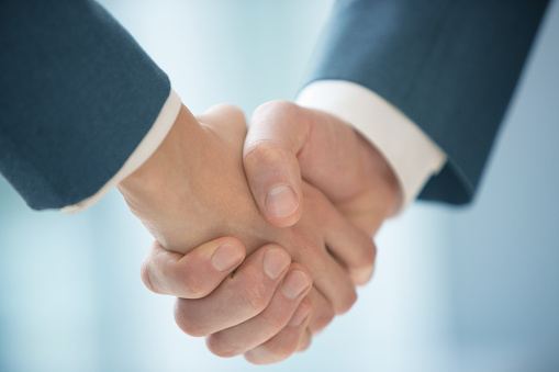 Business persons shaking hands after successful negotiations