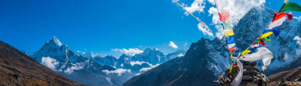 Colourful buddhist prayer flags flying over Himalayan mountain peaks panorama stock photo
