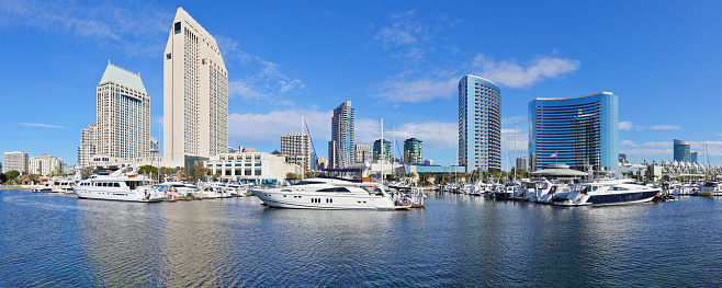 panoramic daytime view of the San Diego skyline and recreational boats in San Diego bay.