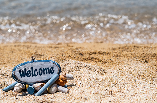 Background beach with sign welcome made of wood and shells