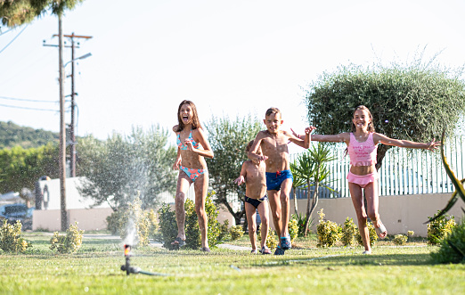 Group of children playing with garden sprayer