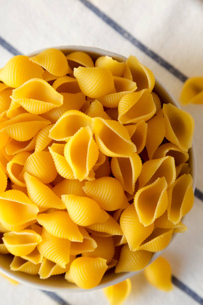 istock Raw Medium Pasta Shells in a Bowl, top view. Flat lay, overhead, from above. Close-up. 1446745983