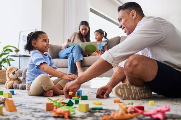 istock Learning, education and family play with blocks with father and creative daughter playing together in living room. Childhood, development or parent, mother or mom reading story book to girl on sofa 1446749317