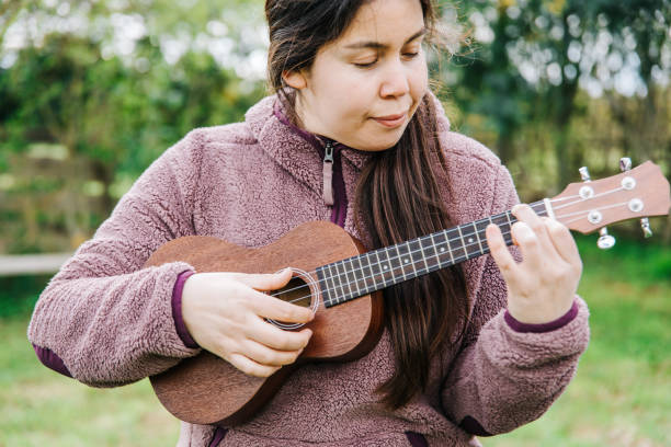 istock Young caucasian woman playing ukelele standing on the grass. 1446749931