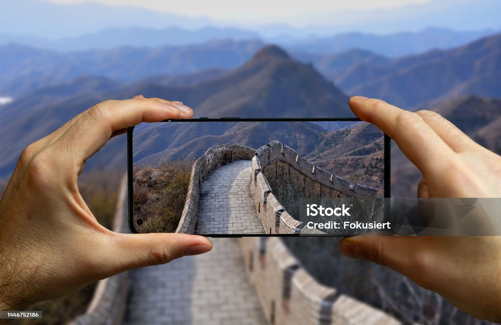 Tourist taking a picture with a mobile phone at the great wall in China. Beijing Stock Photo