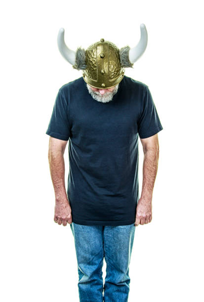 Gray bearded senior man wearing replica of a traditional horned Viking helmet bowing toward the camera. Plenty of copy space on a white background.