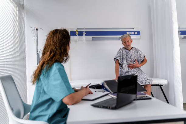 nurse listens intently to her senior male patient - doctor patient male tongue depressor imagens e fotografias de stock