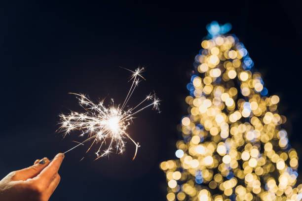 a mão de uma mulher segura uma faísca. celebrações de natal e ano novo - sparkler sparks new years eve human hand - fotografias e filmes do acervo